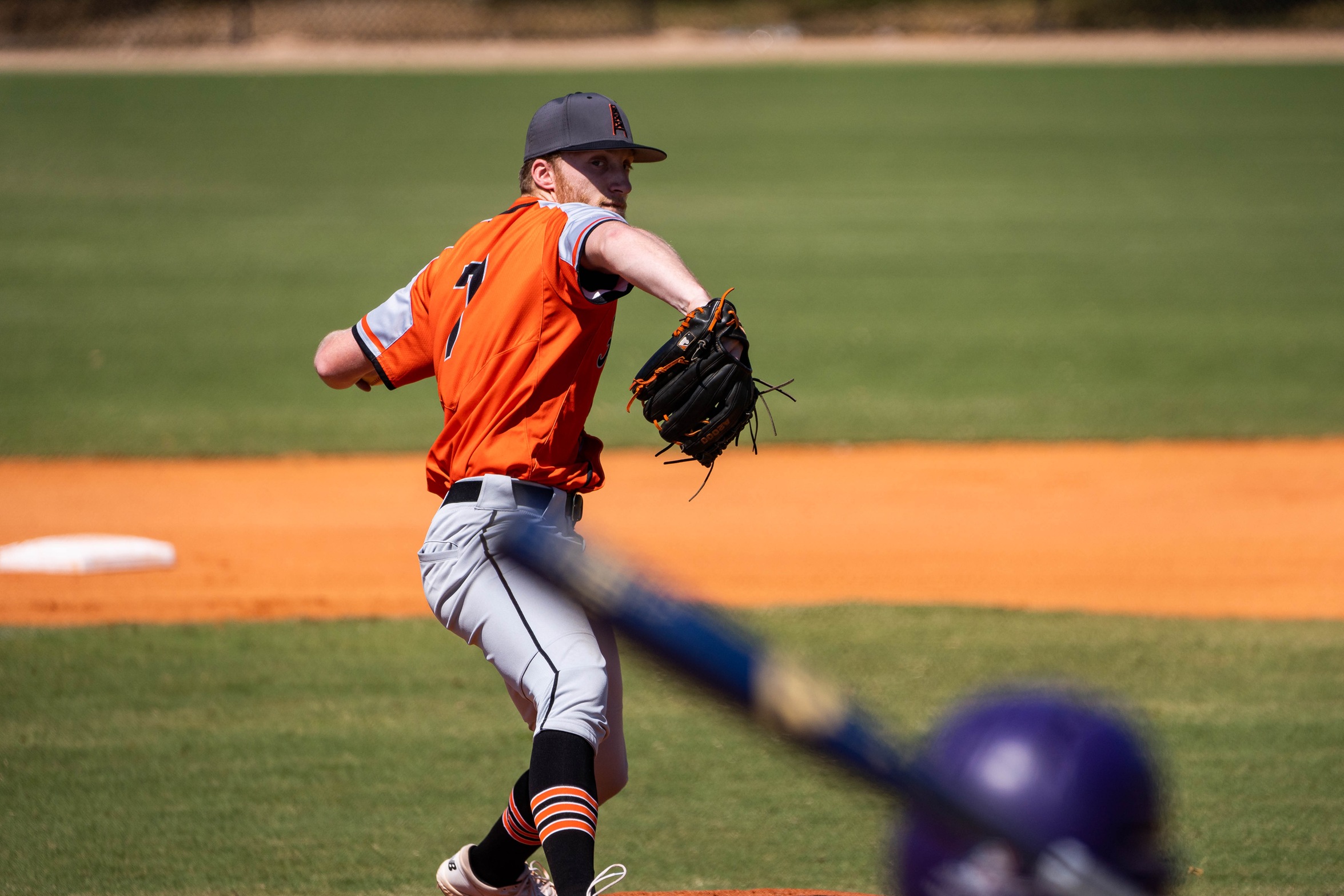 player in orange pitching ball to batter