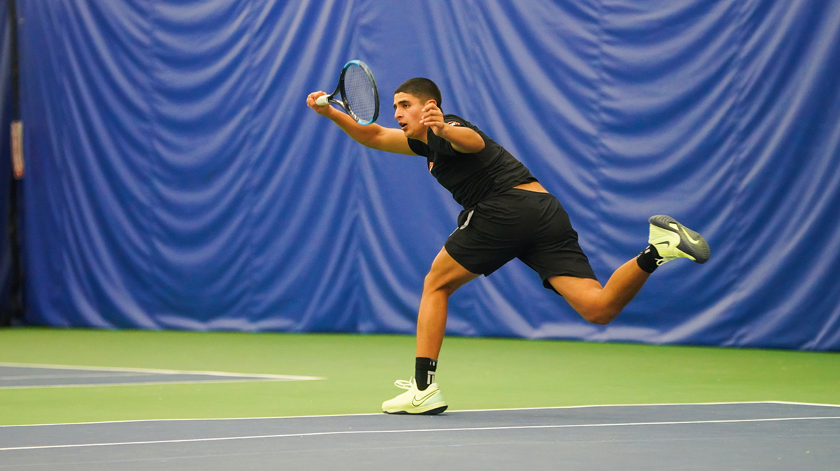 Men's tennis player reaching for a ball
