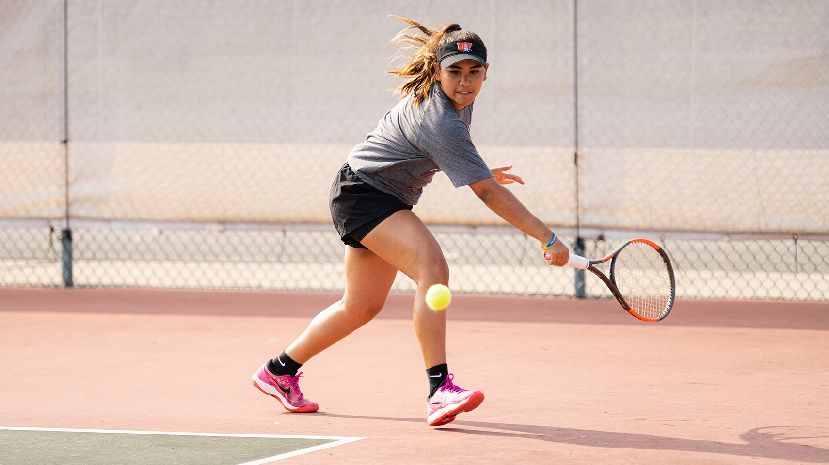 Women's tennis player hitting the ball back handed