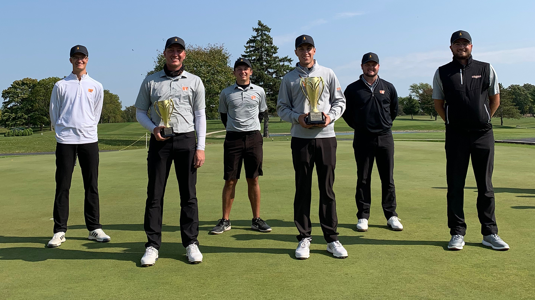 Men's golf team holding trophies while social distancing