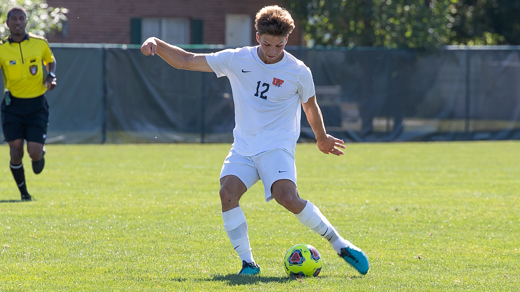 Men's soccer player in white kicking the ball with his left foot