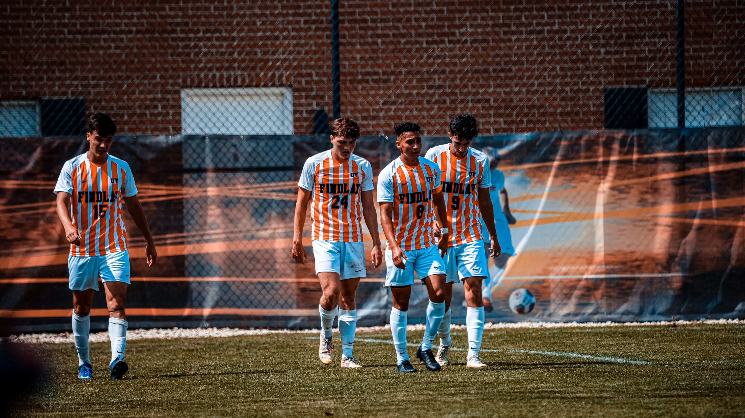 players in white and orange stripes walking