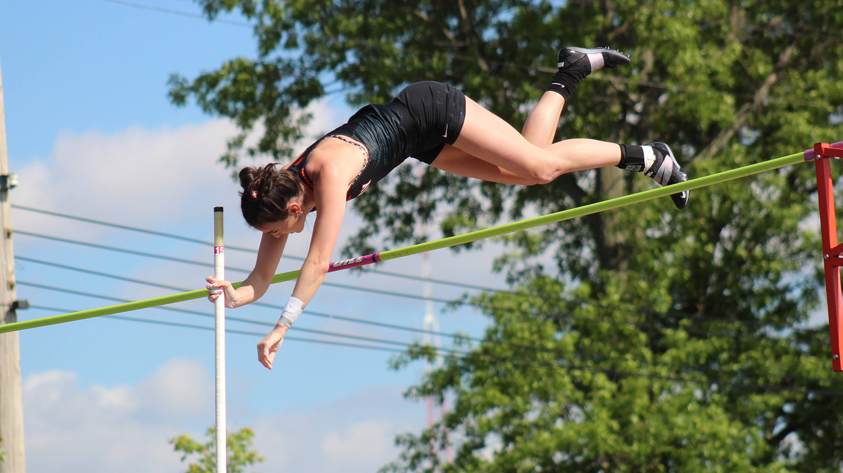 Pole vaulter jumping over the pole in daylight