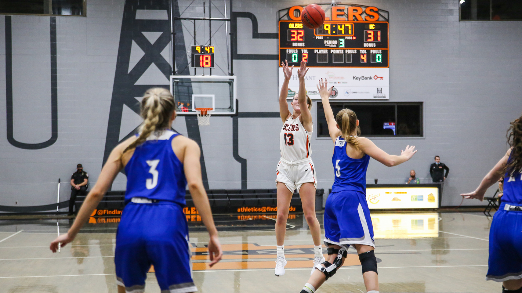 Women's basketball player in white shooting a three pointer.