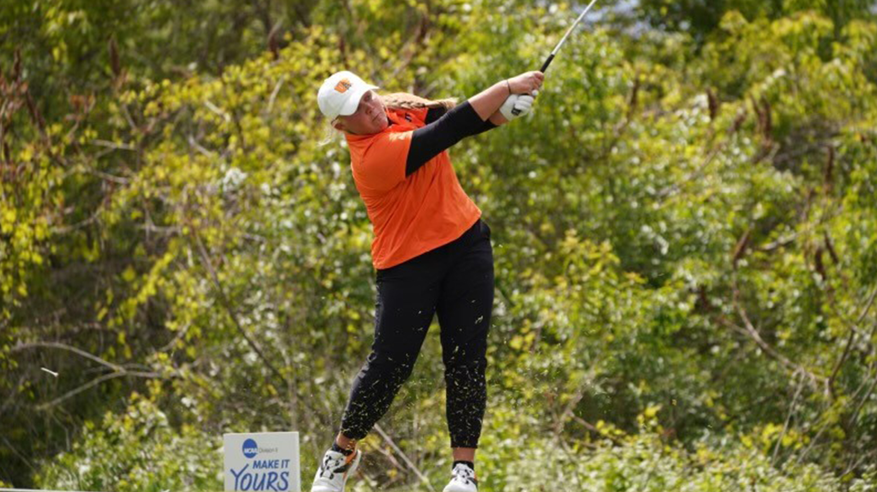 Women's golfer in orange hitting off the tee at the national championship