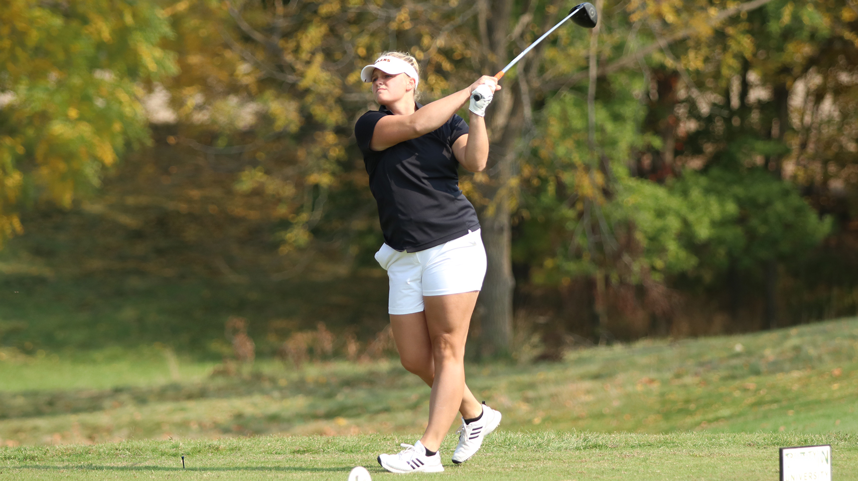 Women's golfer in black hitting the ball off the tee