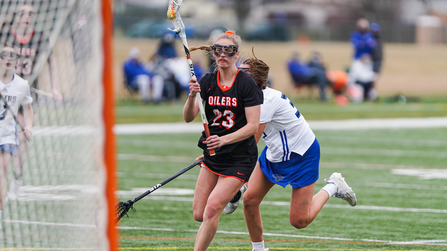 Women's lacrosse player in black shooting the ball