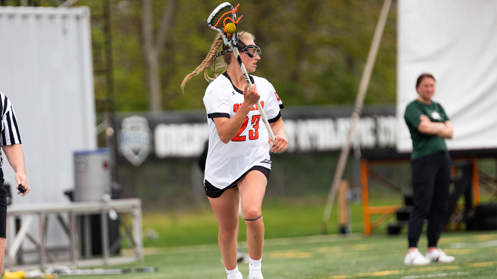 Women's lacrosse player running down the field with the ball