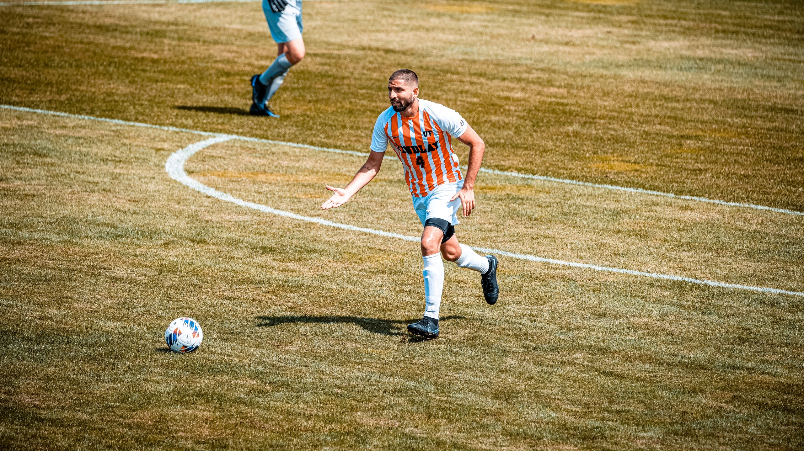 Player in white and orange stripe jersey with ball