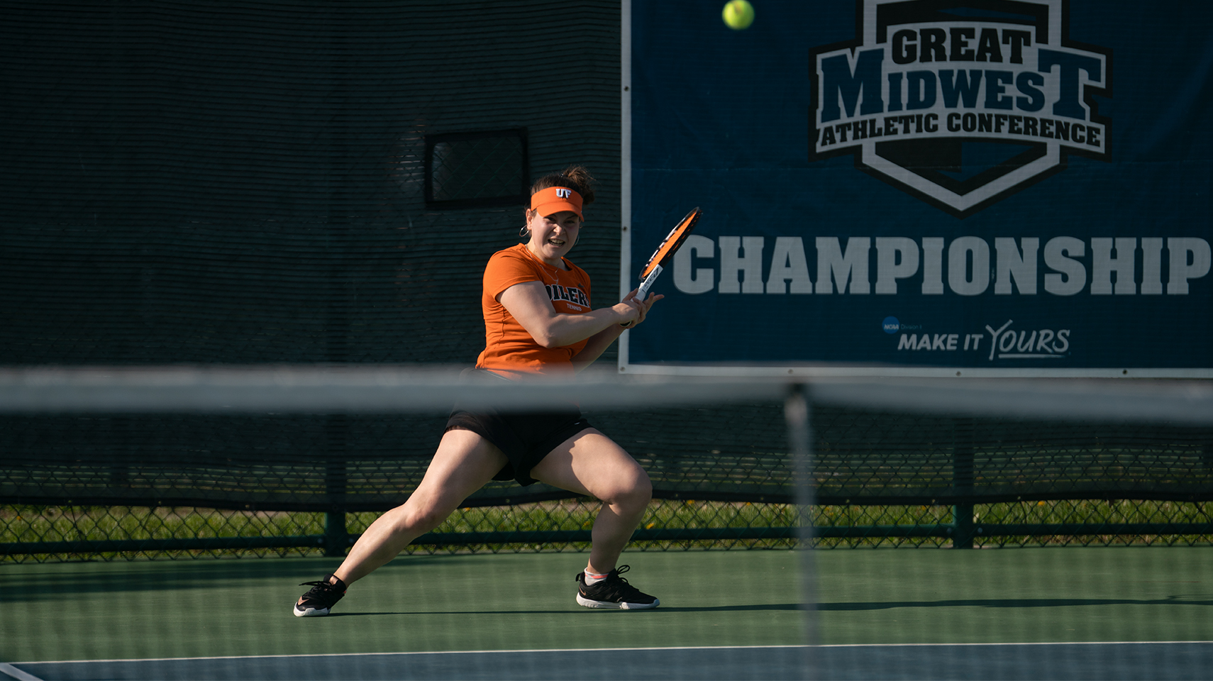Women's tennis player hitting the ball at the G-MAC Tournament in the twilight.