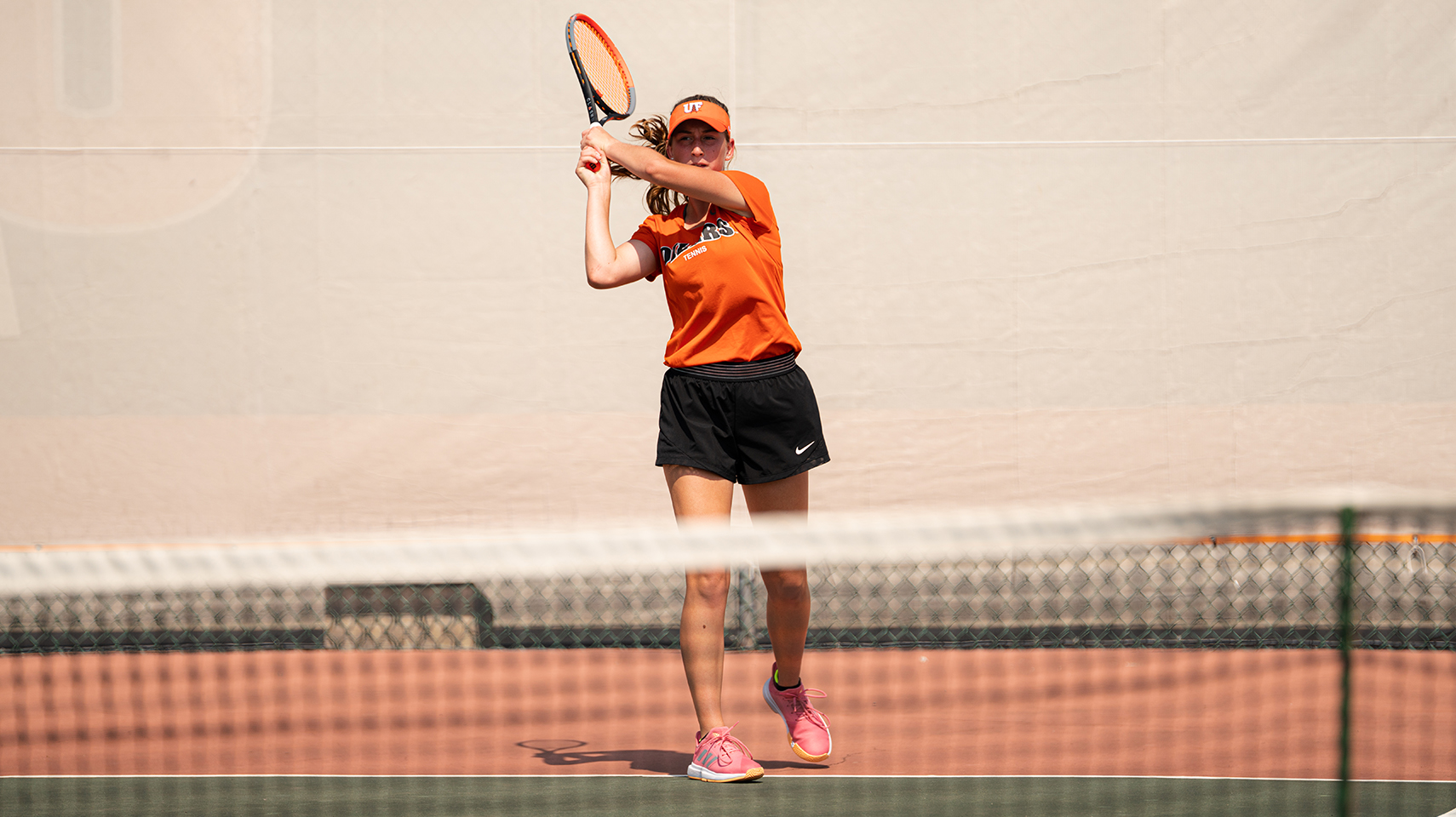 Women's tennis player in orange returning a serve