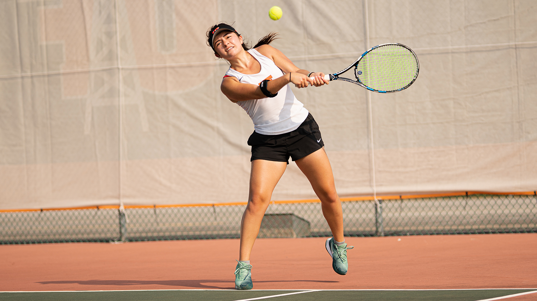 Women's tennis player hitting backhanded off a serve