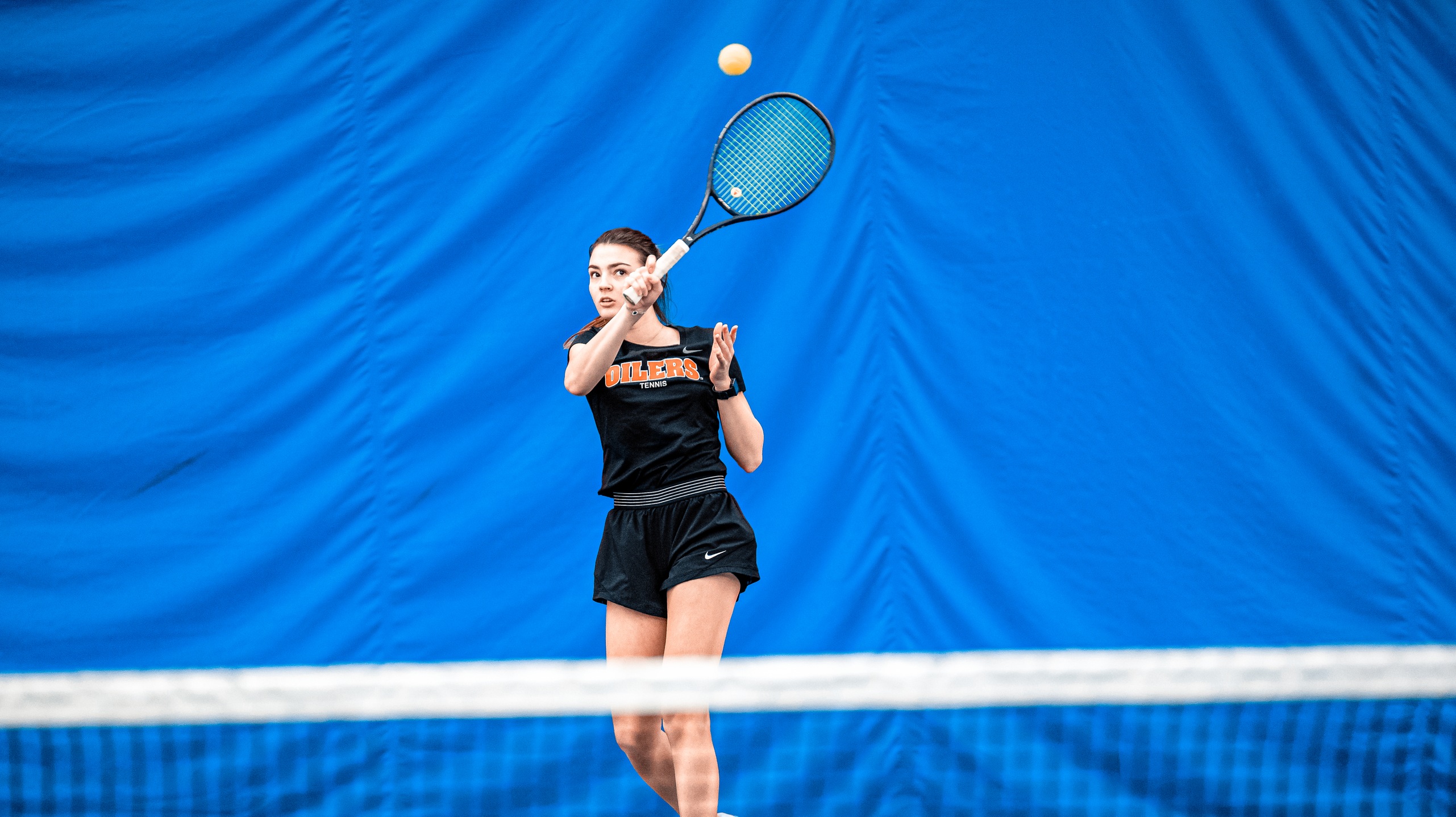 Tennis player wearing balck hitting ball