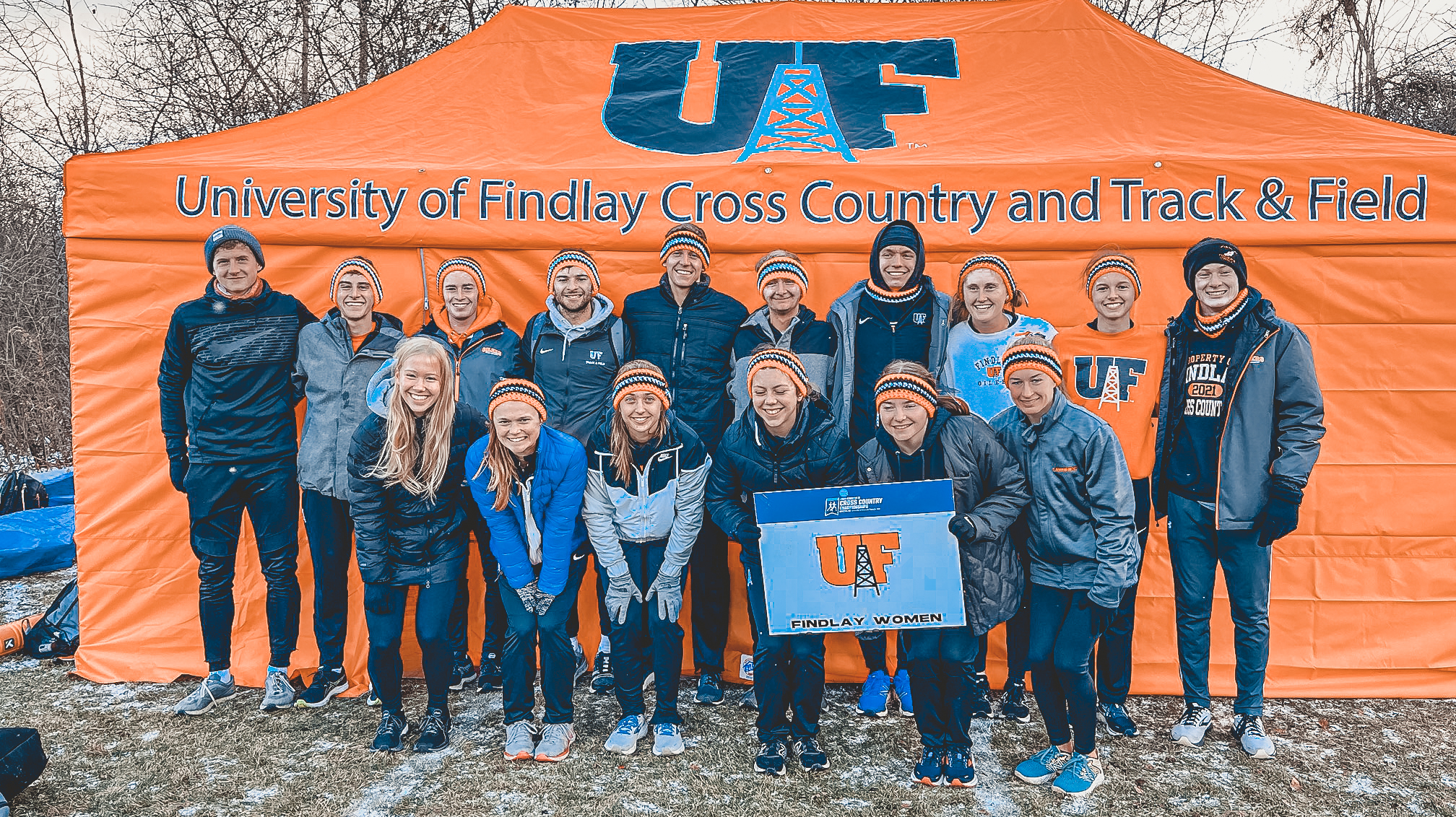cross country team poses in front of team tent