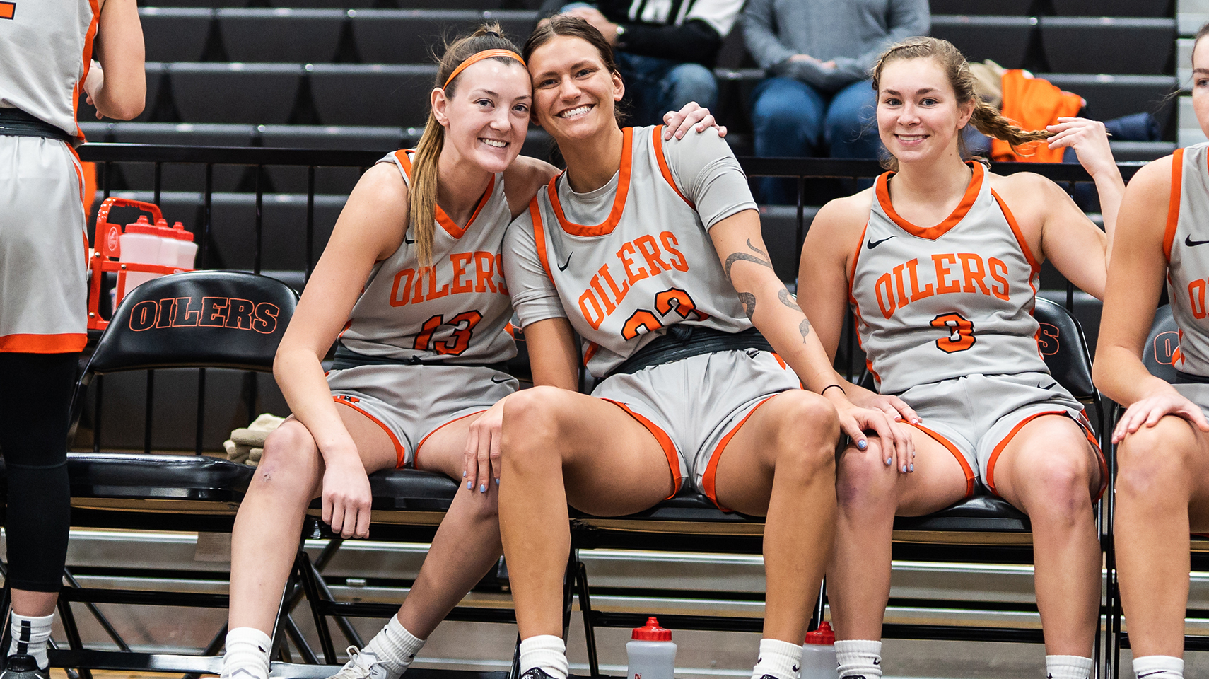 Women's basketball players hugging and smiling on the bench