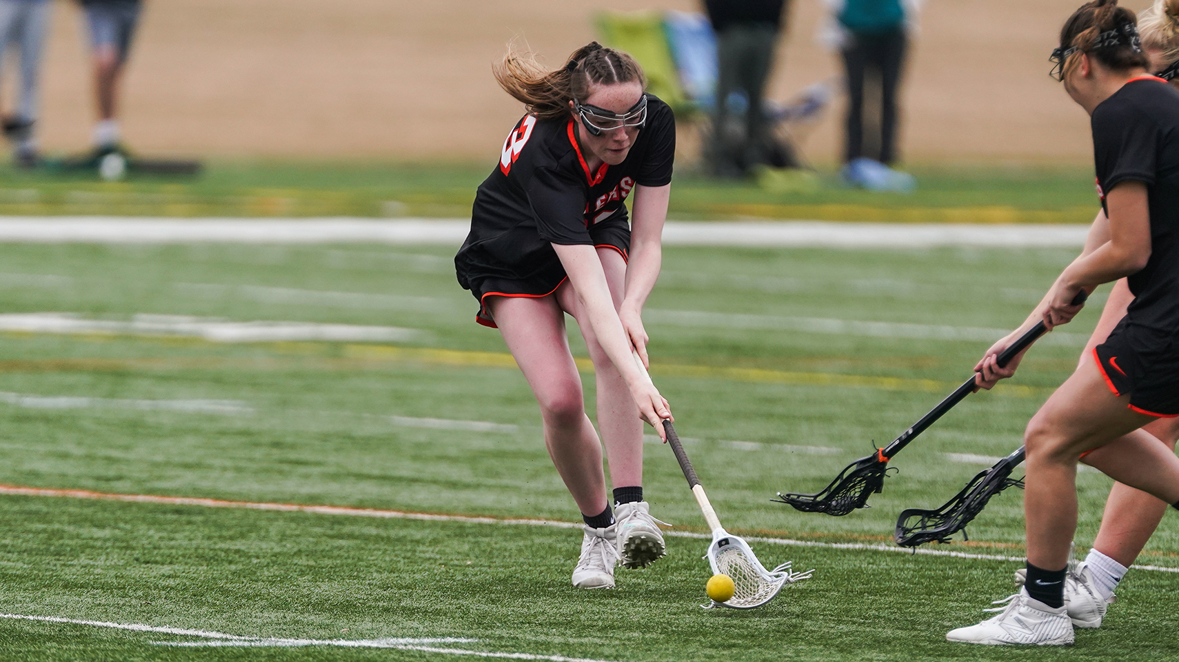 women's lacrosse player picking up a ground ball