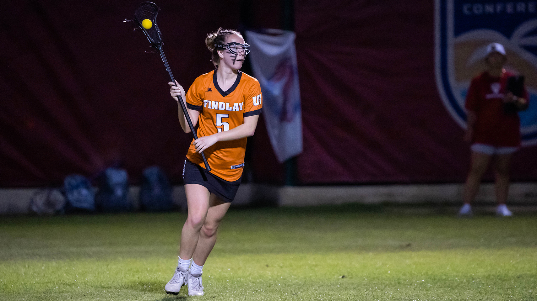 Women's lacrosse player holding the ball at night