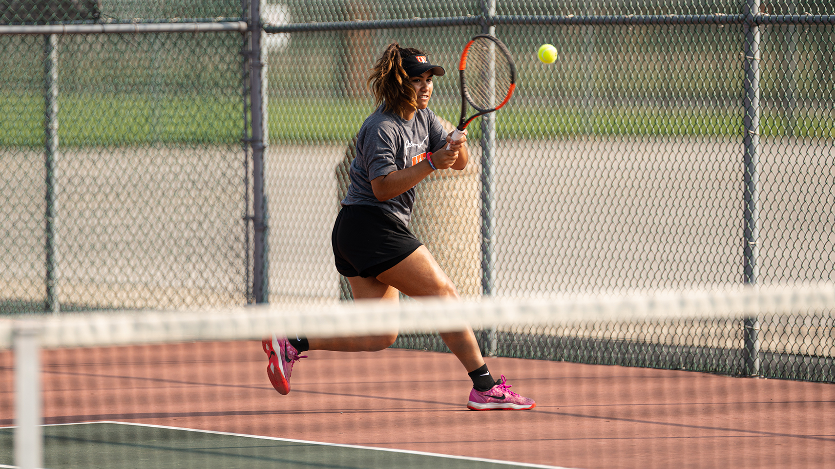 Women's tennis player in gray returning a serve